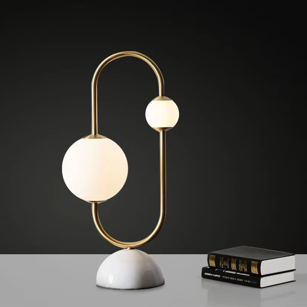 Modern light luxury U-shaped gold frame double-ball table lamp, white glass lampshades + white hemispherical base, soft lighting, creating a minimalist high-end atmosphere.