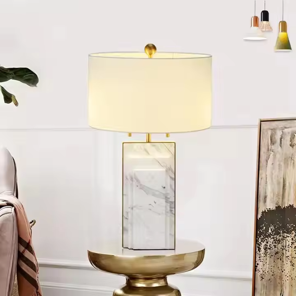 This is a luxury-style black-gold marble table lamp, with a black marble-textured base, golden metal parts, and a beige fabric circular lampshade, featuring a minimalist and grand design with strong luxury texture. It is used for local desktop lighting and decoration, creating a luxury and modern atmosphere. It is suitable for luxury-style home bedroom bedside tables, high-end hotel guest rooms, modern minimalist living room side tables and other places.
