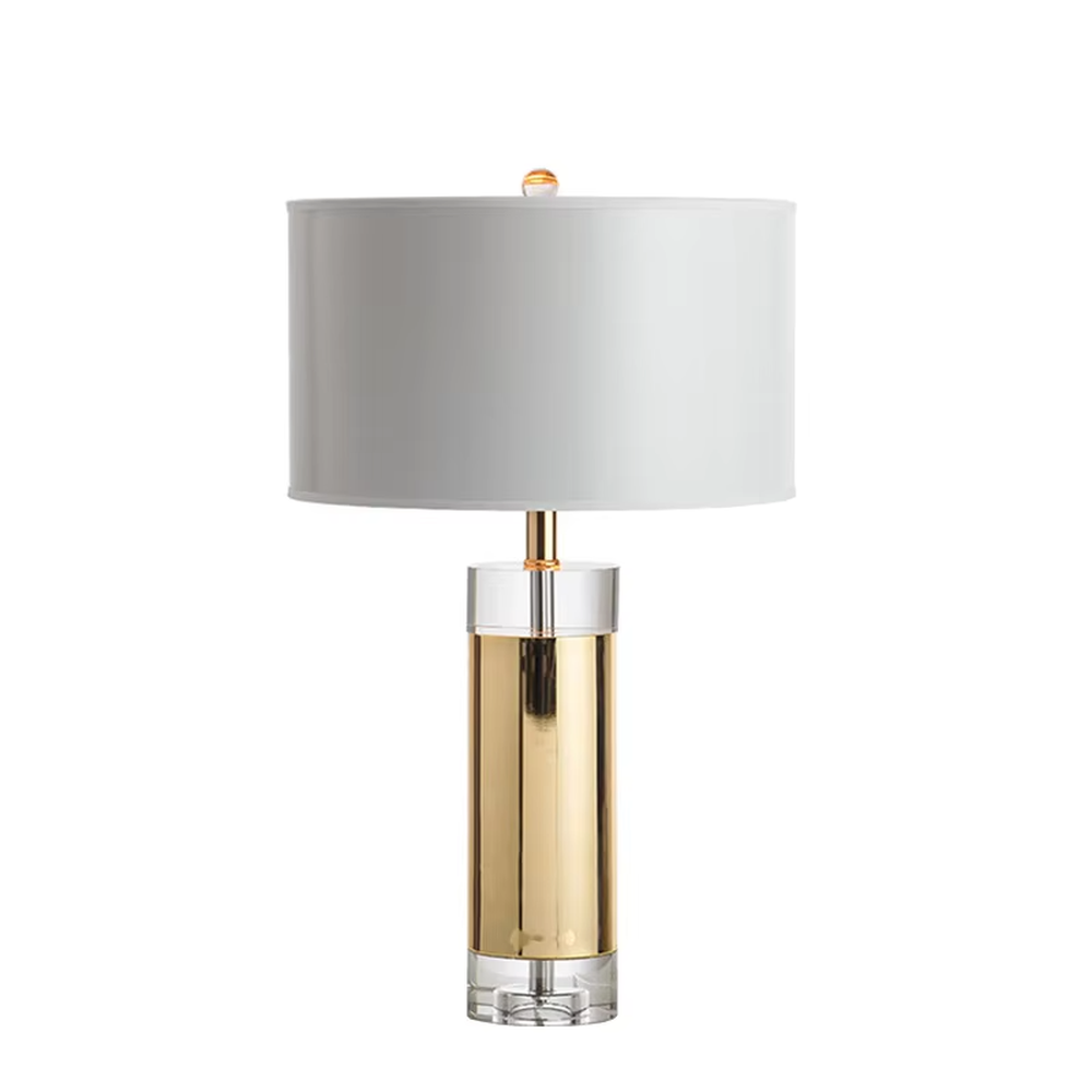 This is a luxury metal crystal table lamp, with a golden metal column, a transparent crystal base, and a white cylindrical fabric lampshade (with golden decoration on top), featuring a luxurious and elegant design with strong modern sense. It is used for local desktop lighting and decoration, creating a high-end luxury atmosphere. It is suitable for luxury-style home bedroom bedside tables, high-end hotel guest rooms, modern soft decoration display spaces and other places.