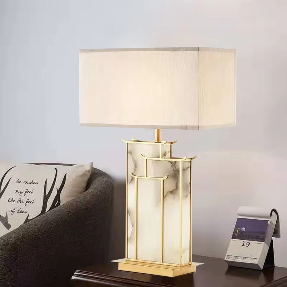 New Chinese light luxury gold frame ink texture table lamp, gold window lattice-like metal frame + ink texture panel + beige fabric lampshade, soft lighting, creating an elegant new Chinese atmosphere.