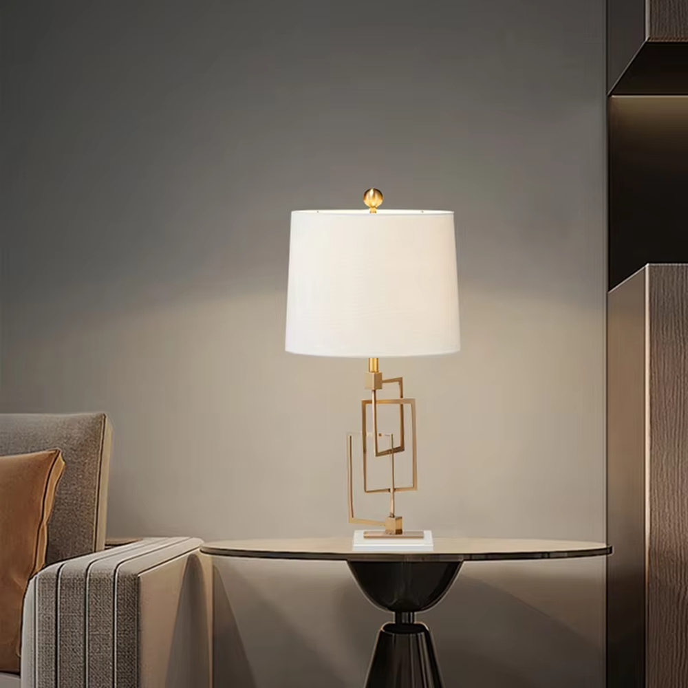 Light luxury modern geometric square frame gold stand table lamp, golden multi-layer square frame stand + beige fabric cylindrical lampshade + white stone base, soft and high-end lighting, creating a light luxury minimalist atmosphere.