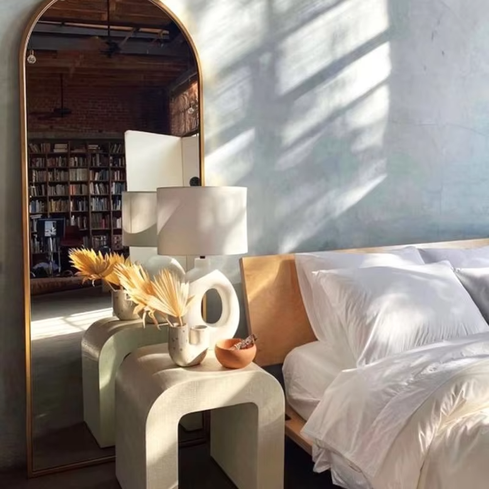 This is a modern artistic white hollow curved table lamp, with a white curved base (featuring a middle hollow design) paired with a white cylindrical lampshade. It has a minimalist artistic style and soft warm lighting.