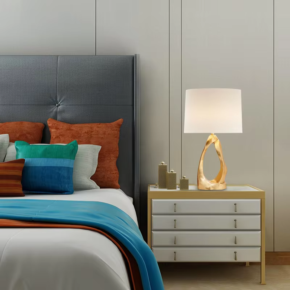 Art light luxury golden irregular twisted hollow base table lamp, beige fabric cylindrical lampshade, soft warm light, creating a high-end art light luxury atmosphere.