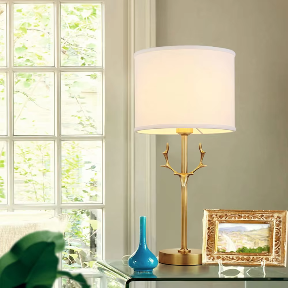Light luxury golden antler-shaped table lamp, white cylindrical fabric lampshade + golden base, soft and warm lighting, creating a natural elegant atmosphere.