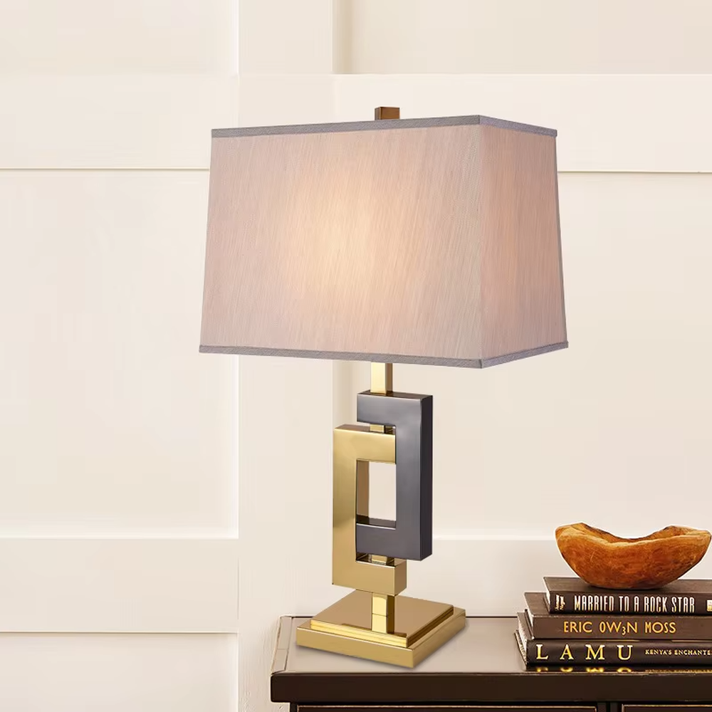 Light luxury gold-gray color-blocking geometric square frame table lamp, gold + dark gray metal geometric stand + dark gray fabric rectangular lampshade, soft and high-end lighting, creating a light luxury modern atmosphere.