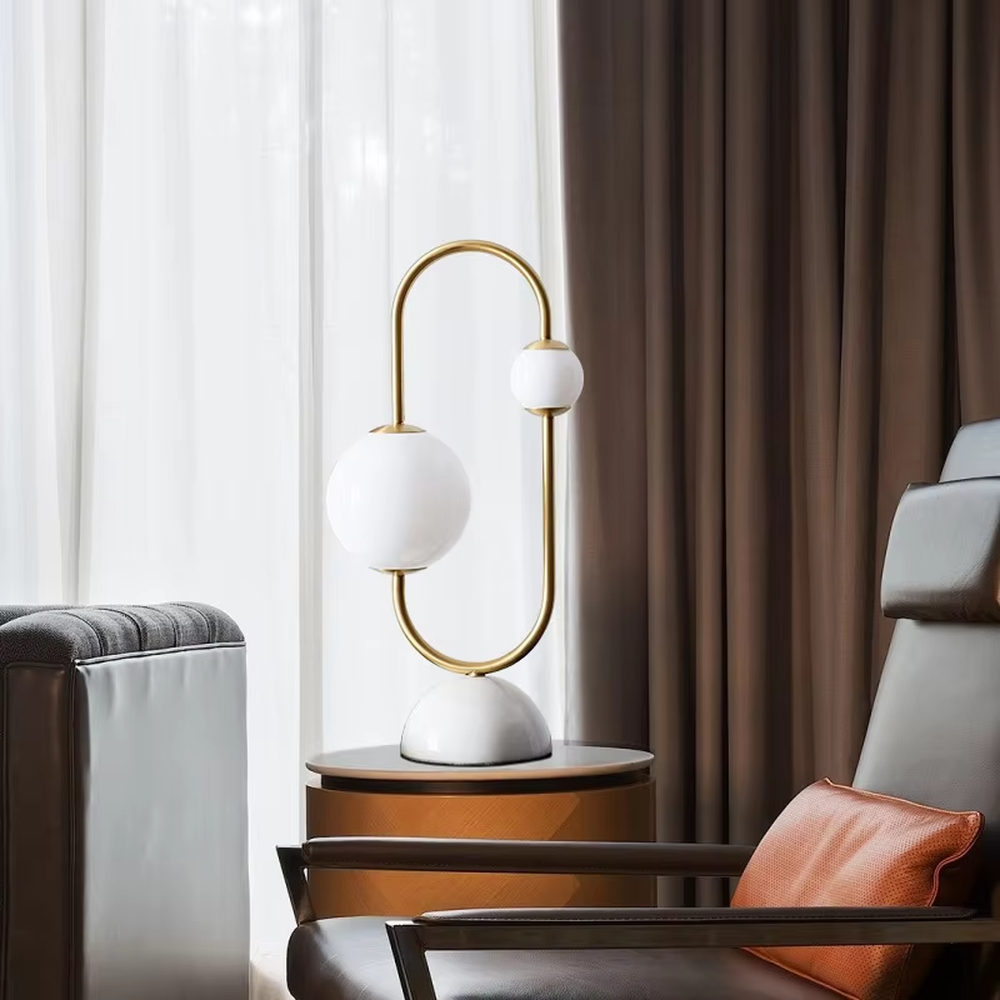 Modern light luxury U-shaped gold frame double-ball table lamp, white glass lampshades + white hemispherical base, soft lighting, creating a minimalist high-end atmosphere.