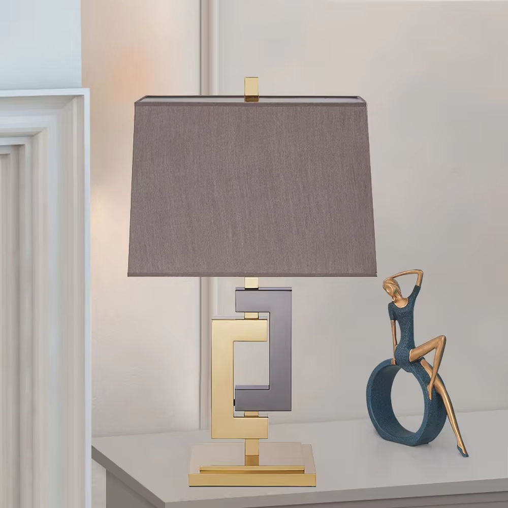 Light luxury gold-gray color-blocking geometric square frame table lamp, gold + dark gray metal geometric stand + dark gray fabric rectangular lampshade, soft and high-end lighting, creating a light luxury modern atmosphere.