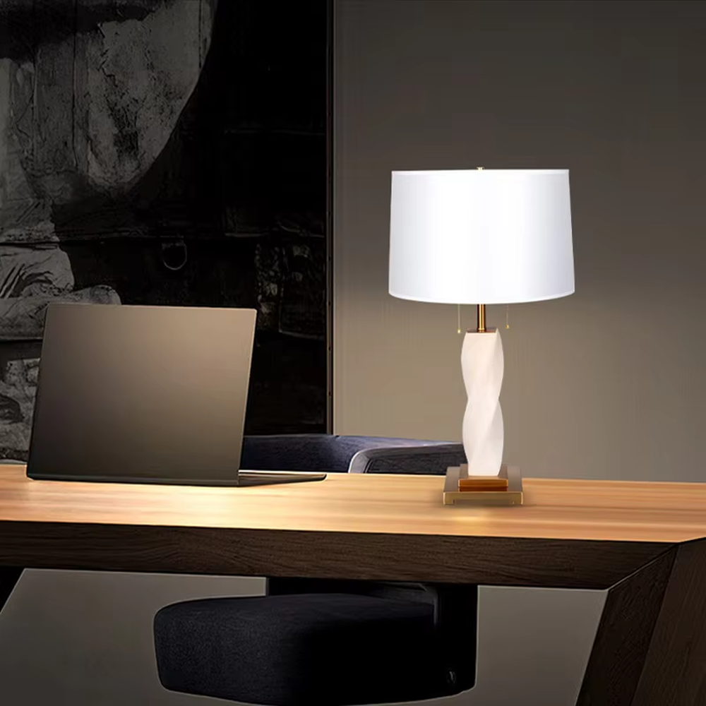 This is a modern artistic twisted table lamp, with a white twisted base, golden metal components, and a white fabric circular lampshade, featuring a strong artistic sense and luxury texture. It is used for local desktop lighting and decoration, creating an artistic luxury atmosphere. It is suitable for modern art home bedroom bedside tables, designer studios, high-end hotel guest rooms and other places.