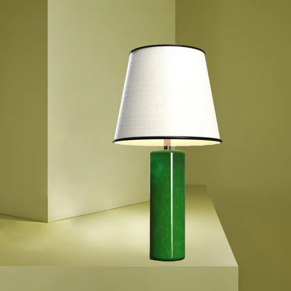 This is a modern fresh-style green cylindrical table lamp, with a green cylindrical base and a white fabric lampshade (black edging), featuring a minimalist modern design and fresh style. It is used for local desktop lighting and decoration, creating a fresh and modern atmosphere. Suitable for modern minimalist bedroom bedside tables, Nordic-style living room side tables, creative studios and other places.