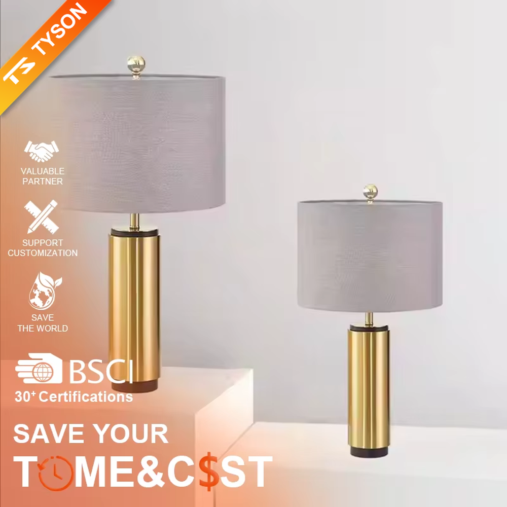 This is a light luxury minimalist golden cylinder table lamp, with a golden metal cylinder base paired with a light purple textured fabric lampshade, decorated with a small golden ball on top. The lighting is soft and warm, creating an elegant light luxury atmosphere.