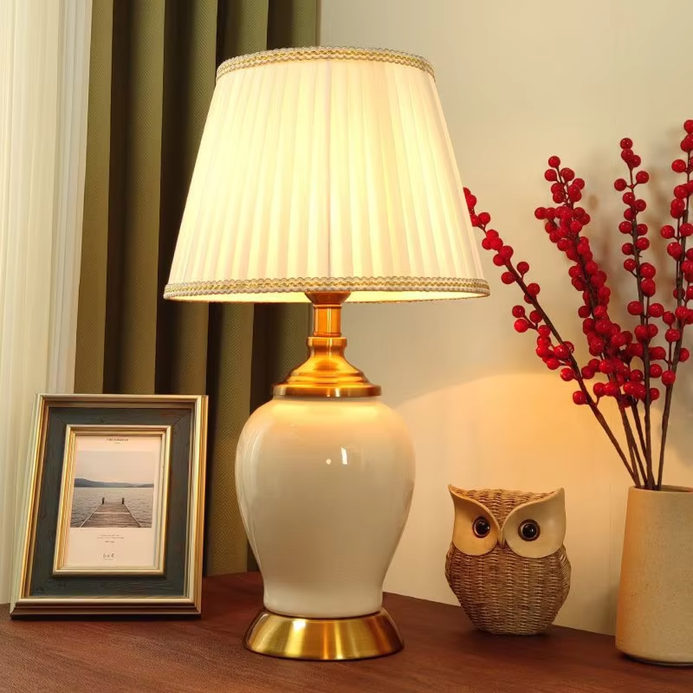 Vintage elegant-style beige pleated fabric lampshade table lamp, white porcelain vase base + golden metal decorations, soft and warm lighting, creating an elegant and cozy atmosphere.