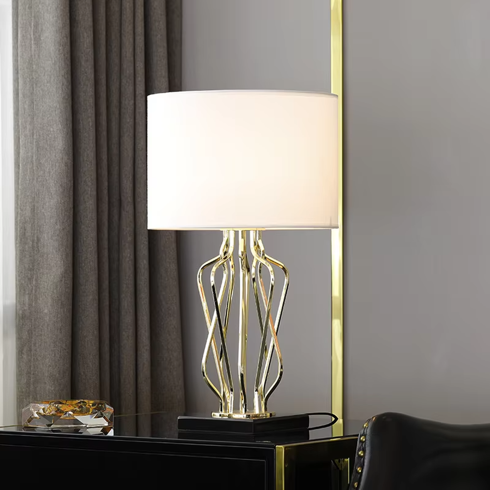 Light luxury golden interlaced hollow table lamp, white cylindrical fabric lampshade + black base, soft and warm lighting, creating a high-end elegant atmosphere.