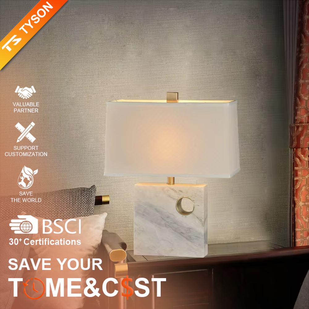 This is a light luxury elegant marble-based fabric table lamp, with a white marble base with golden ring decoration, paired with a beige fabric square lampshade and golden metal connectors. It features a minimalist light luxury design, with warm and soft lighting. It is used for local desktop lighting and decoration, creating a light luxury elegant atmosphere. Suitable for light luxury-style bedroom bedside tables, modern minimalist studies, high-end hotel guest rooms and other places.