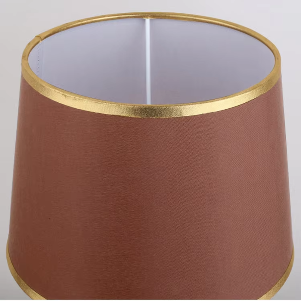 Modern light luxury fabric table lamp, with an off-white fabric lampshade (with gold trim on the top and bottom edges) paired with a black-gold spliced lamp pole and a black disc base, emitting soft and warm light, combining decorativeness and practicality, suitable for lighting and decoration in spaces such as bedroom nightstands, living room side tables, and studies.