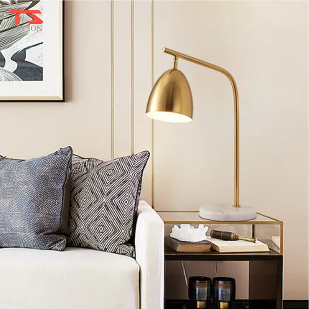 This is a modern light luxury style table lamp, with a gold metal curved arm paired with a dome-shaped lampshade, and a white marble base, which has both lighting and decorative functions, suitable for study desks, bedroom nightstands, office spaces, etc.