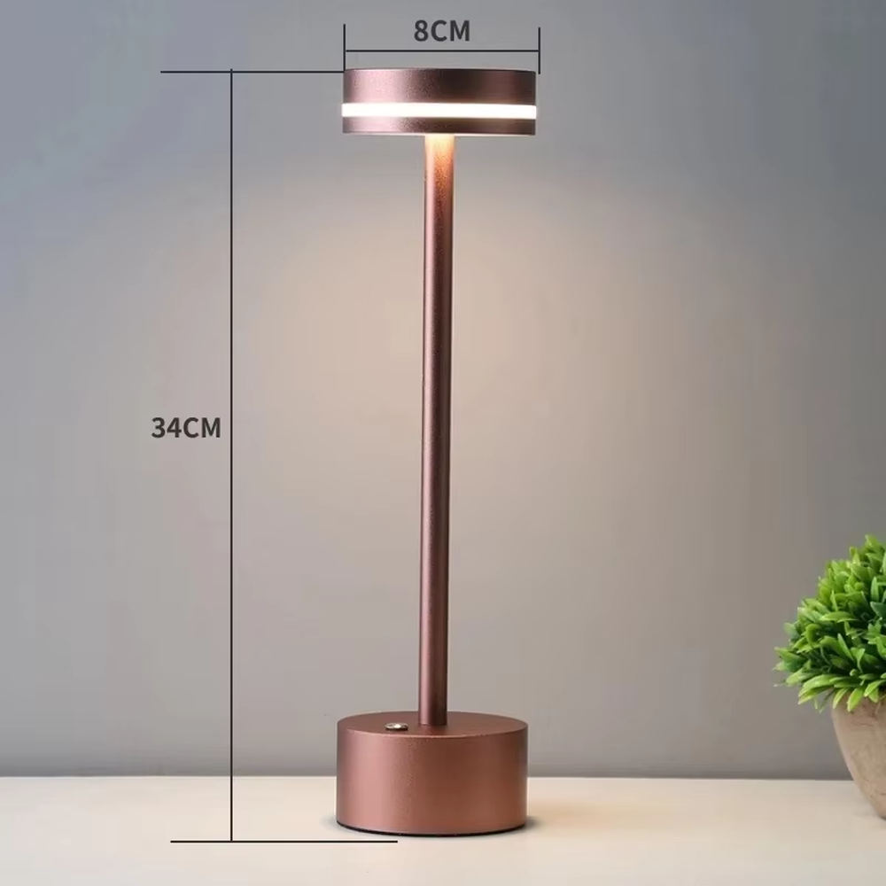 Modern minimalist bronze metal rechargeable table lamp, featuring a cylindrical lamp body and a top ring-shaped lighting design, emitting soft and even light. It supports wireless battery life and touch dimming, suitable for ambient lighting and supplementary lighting in scenarios such as dining tables, bars, and bedroom nightstands.