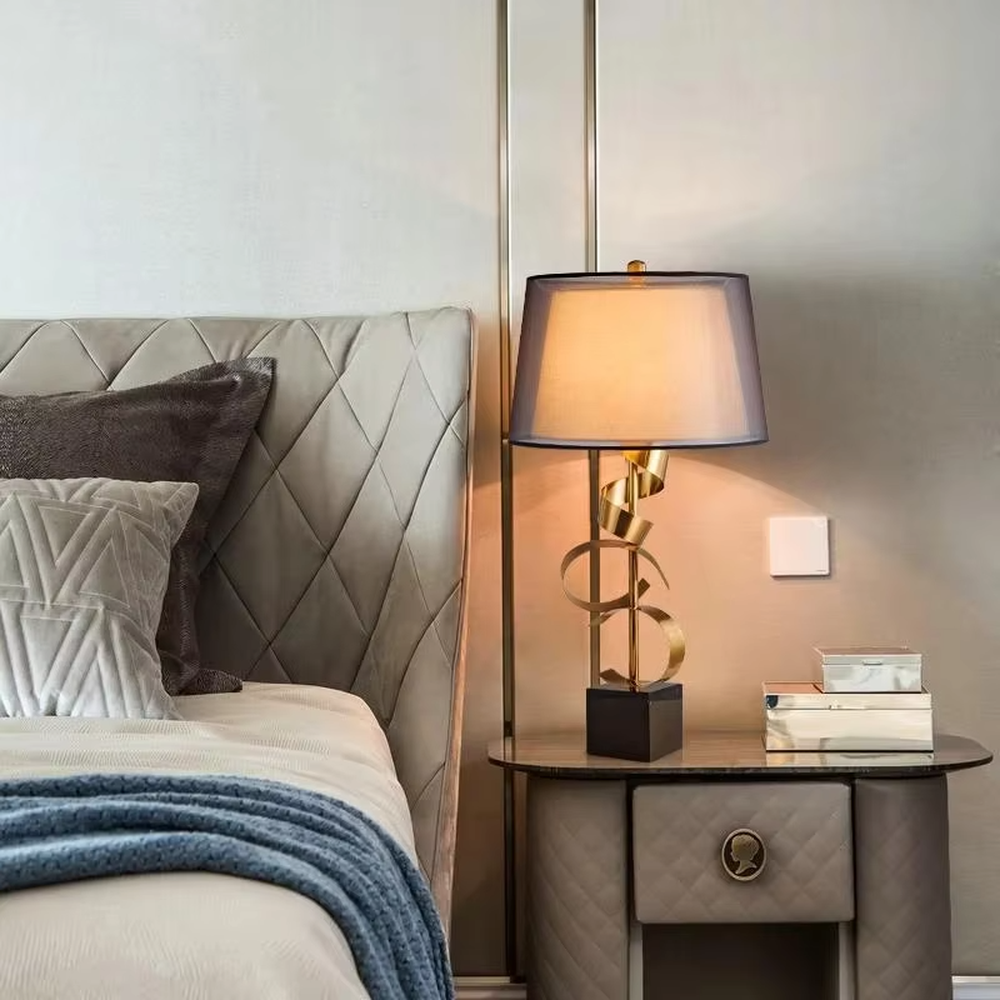 Light luxury golden spiral-shaped table lamp, golden spiral stand + black square base + gradient gray fabric lampshade, soft warm light, creating an elegant light luxury bedroom atmosphere.