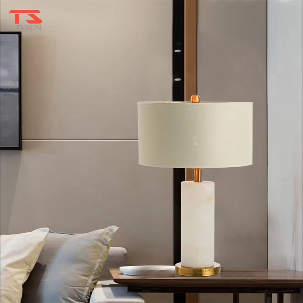 This is a light luxury minimalist table lamp, featuring a natural marble lamp post paired with gold metal accents and an off-white fabric lampshade. It emits soft and gentle light, serving both lighting and decorative purposes, suitable for bedroom nightstands, hotel guest rooms, light luxury living room side tables, showrooms and other scenarios.