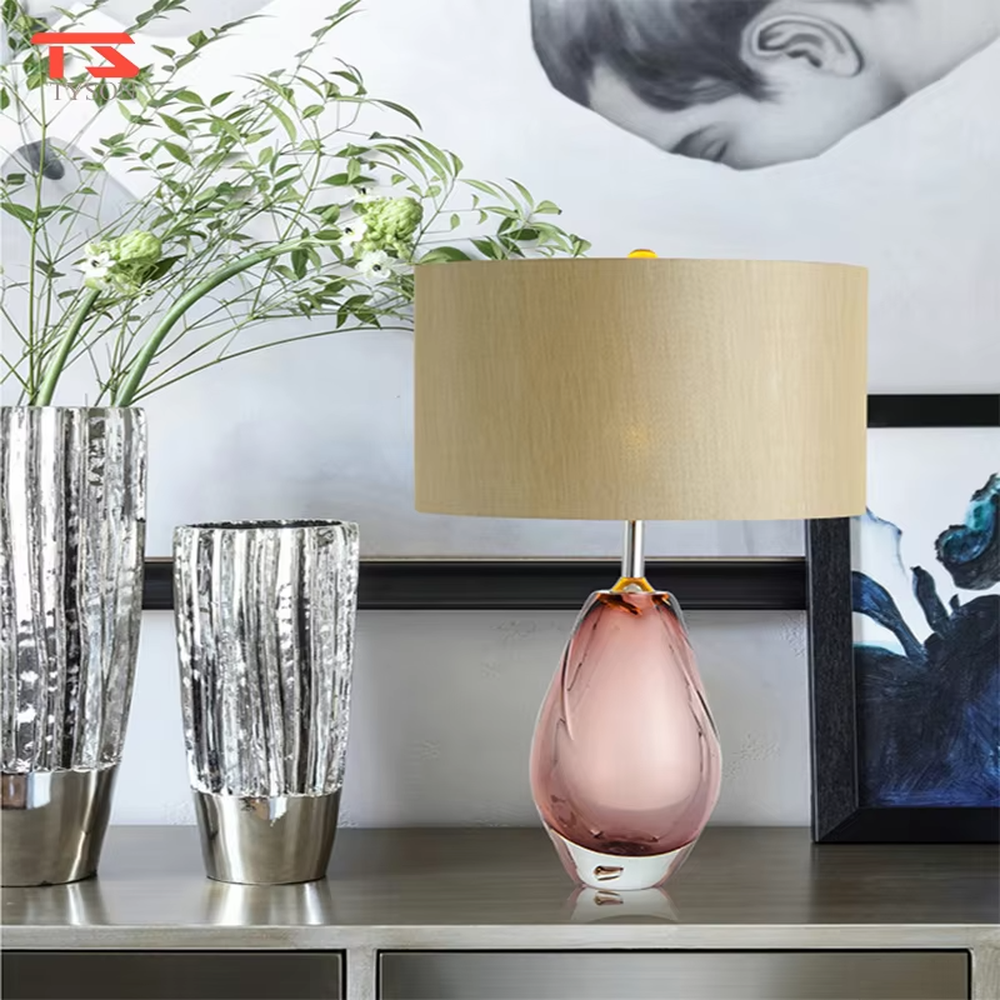 Modern art pink waterdrop glass base beige fabric shade table lamp, warm light effect, creating an elegant artistic atmosphere.