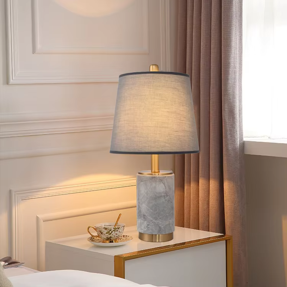 Light luxury white marble cylindrical table lamp, white marble base + golden metal decorations + beige fabric lampshade, soft warm light, creating an elegant light luxury home atmosphere.