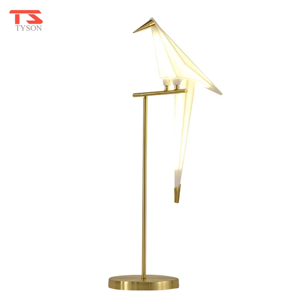 This is a modern light luxury origami crane-shaped table lamp, featuring a gold metal stand paired with a translucent paper art lamp body. The lamp body is as dynamic and soft as an origami crane, serving both lighting and artistic decoration purposes, suitable for bedroom nightstands, light luxury living room side tables, hotel guest rooms, showrooms and other scenarios.