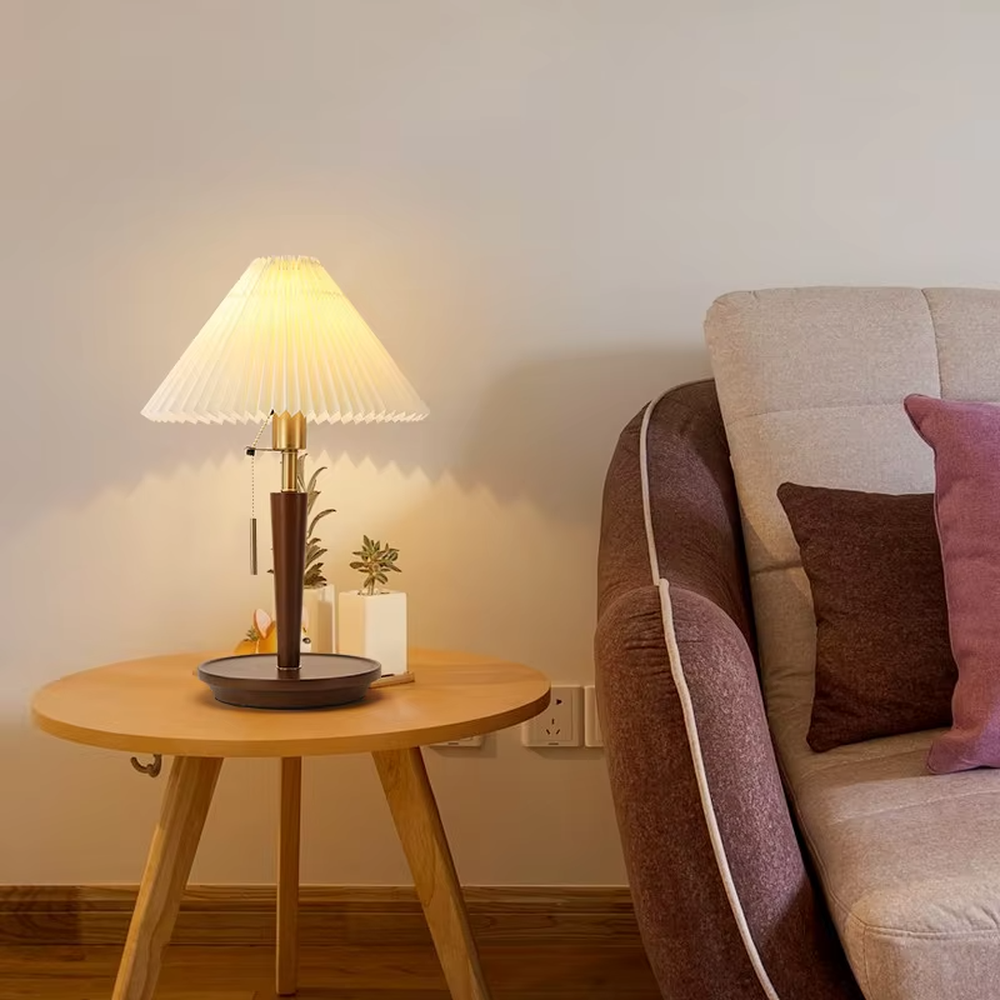 Vintage Nordic pleated fabric table lamp, with an off-white pleated fabric lampshade paired with a dark brown wood and gold metal spliced lamp pole, featuring a pull-cord switch, emitting soft and warm light, combining decorativeness and practicality, suitable for lighting and decoration in spaces such as bedroom nightstands, living room side tables, and B&B guest rooms.