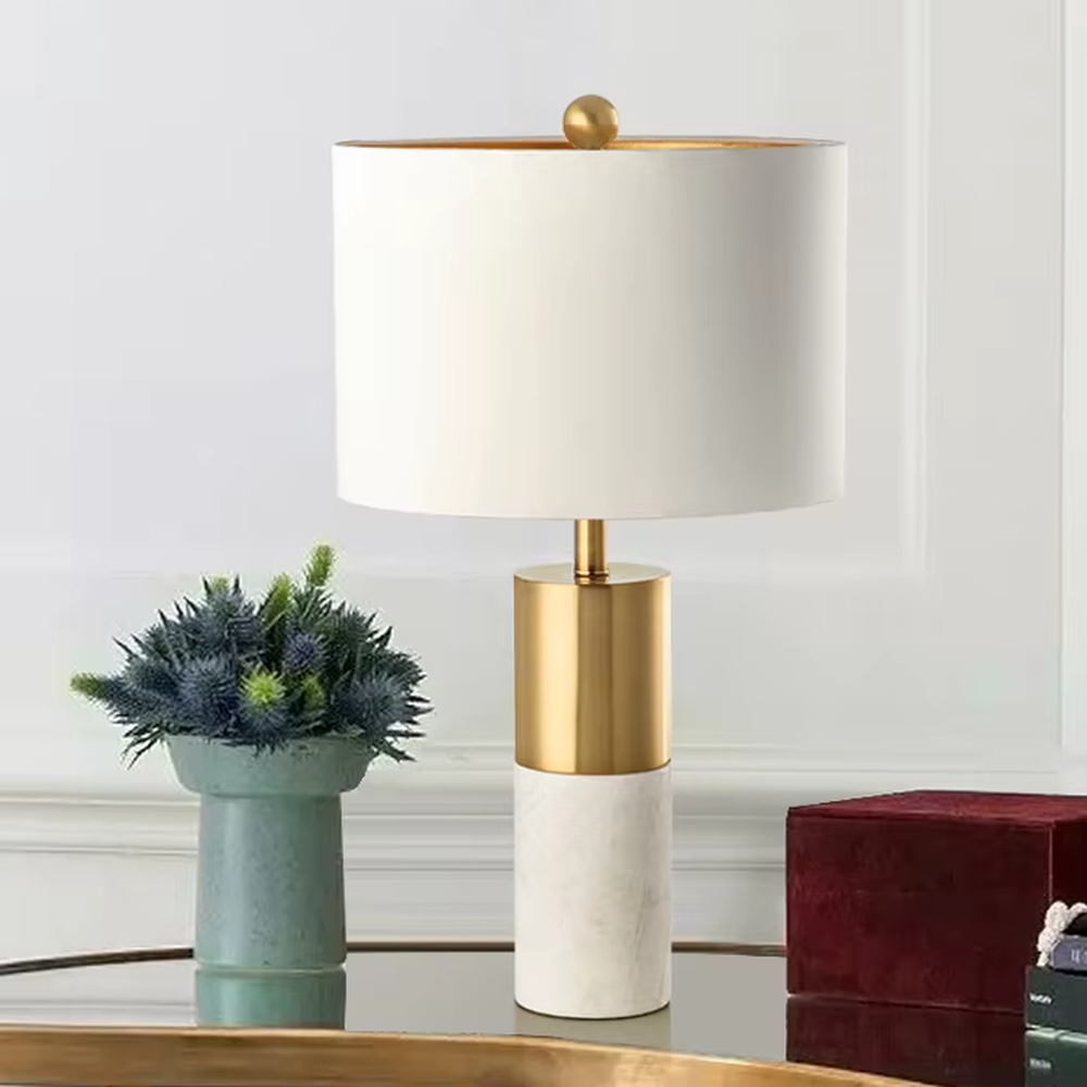 This light luxury table lamp features a black marble (with white veins) base, paired with a gold metal cylindrical lamp body and an off-white fabric cylindrical lampshade, with a gold spherical decoration on top. It serves both lighting and decorative purposes, ideal for light luxury spaces such as bedroom bedside tables, living room side tables, and hotel guest rooms.