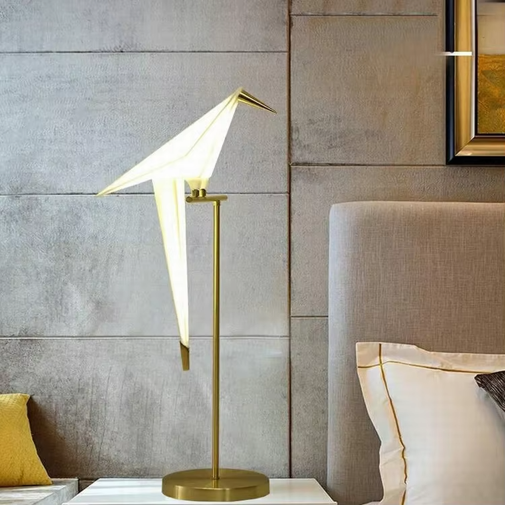 This artistic origami crane-shaped table lamp features a gold metal stand and base, paired with a translucent material to create an origami crane lampshade. It serves both lighting and decorative purposes, ideal for light luxury art-style spaces such as bedroom bedside tables, living room side tables, and hotel guest rooms.