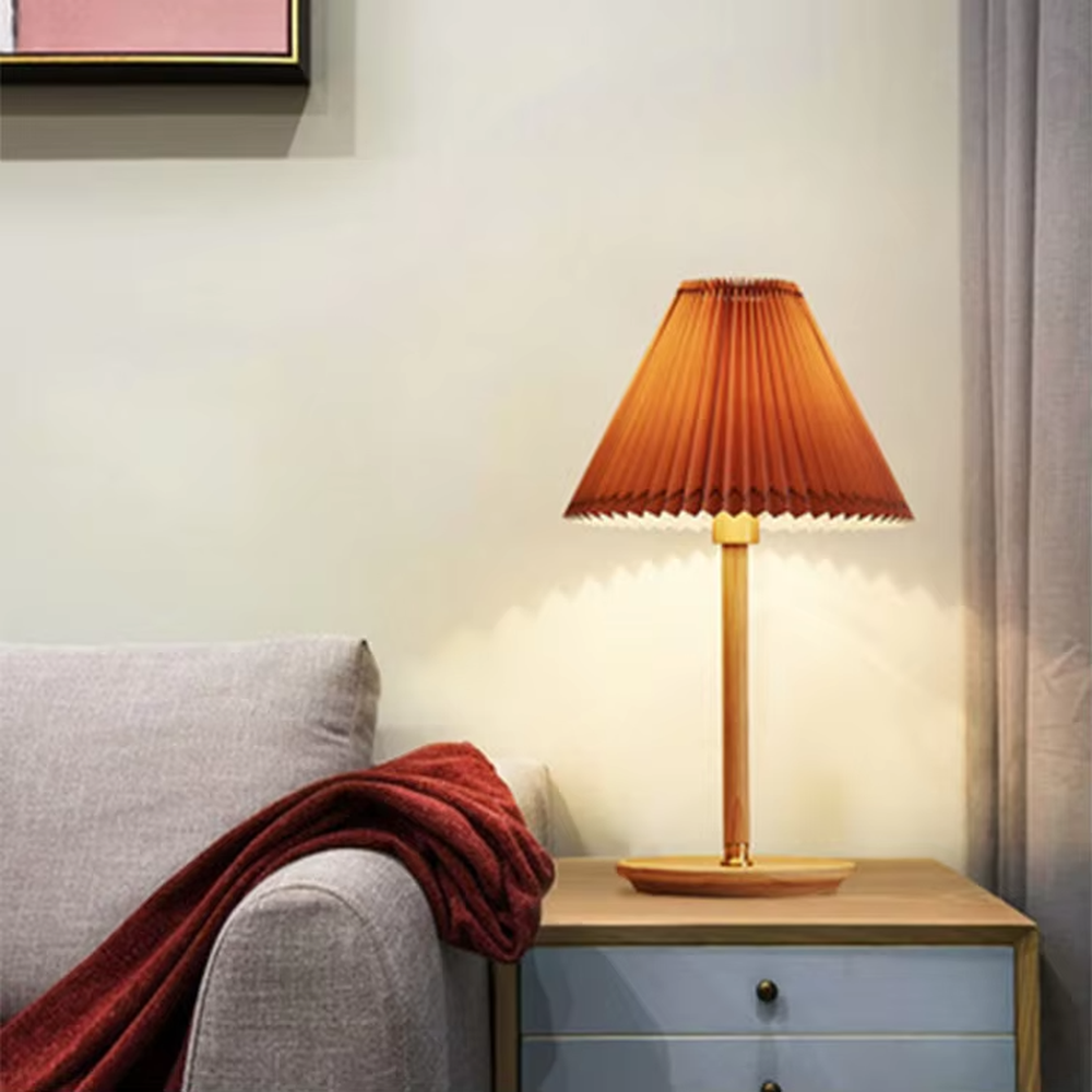 Nordic-style wooden pleated table lamp, with a light wood lamp pole and base paired with an orange pleated fabric lampshade, providing soft and warm light, designed to enhance the cozy atmosphere of spaces, suitable for bedroom nightstands, living room side tables, homestay guest rooms, etc.