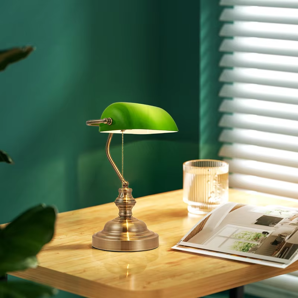 Vintage industrial-style green shade brass adjustable table lamp, semi-circular green shade + brass metal stand + pull chain switch, soft warm light creates vintage atmosphere.