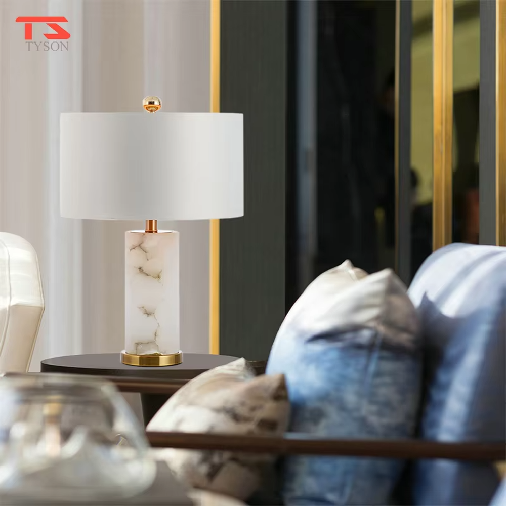This is a light luxury minimalist table lamp, featuring a natural marble lamp post paired with gold metal accents and an off-white fabric lampshade. It emits soft and gentle light, serving both lighting and decorative purposes, suitable for bedroom nightstands, hotel guest rooms, light luxury living room side tables, showrooms and other scenarios.