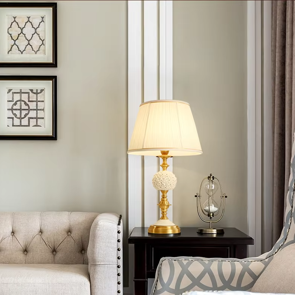 This European light luxury table lamp features a glossy gold metal base, paired with hollow carved crystal decorations and an off-white pleated fabric lampshade, presenting a luxurious and retro court texture. The light is soft and warm, serving both lighting and decorative purposes, suitable for placement in European-style spaces such as bedrooms and villa guest rooms.