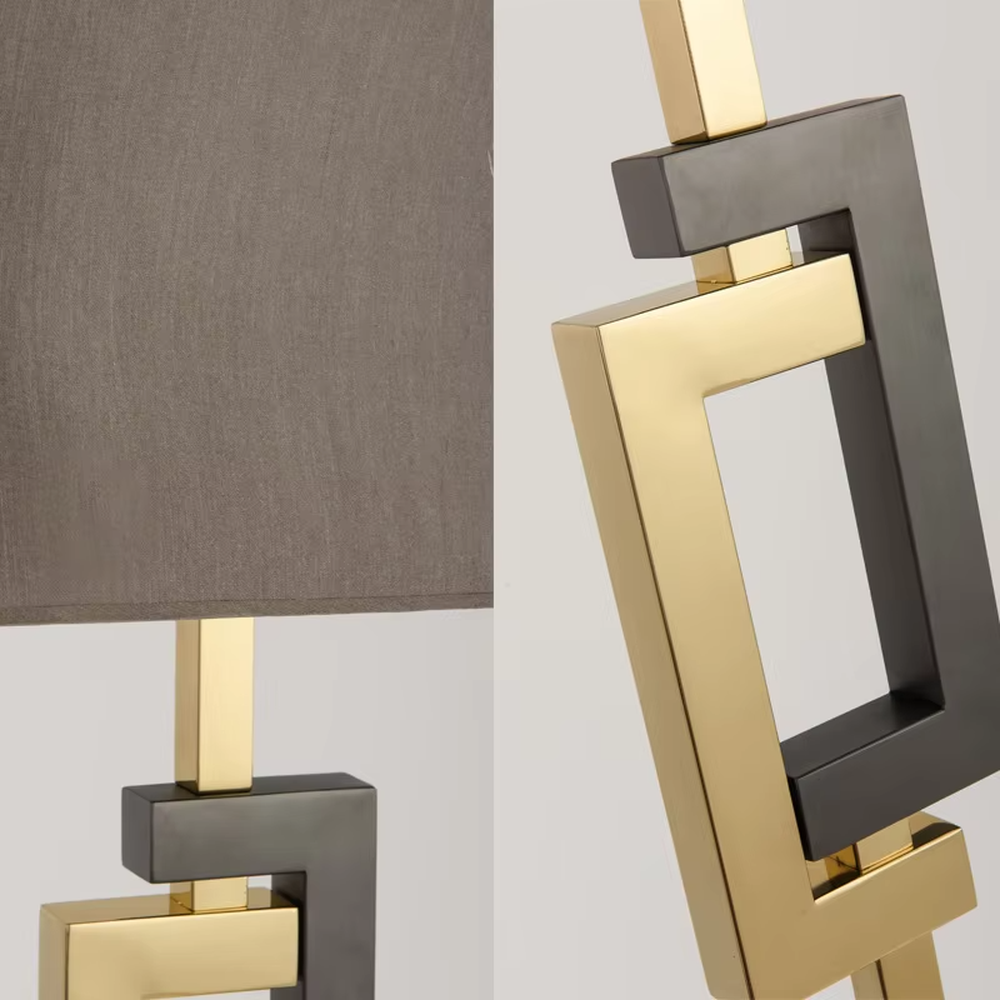 This is a modern light luxury geometric interlocking table lamp, featuring an interlocking geometric lamp body crafted from gold and gray dual-color metal, paired with a dark gray fabric lampshade. It emits soft and uniform light, serving both lighting and decorative purposes, suitable for bedroom nightstands, light luxury living room side tables, hotel guest rooms, showrooms and other scenarios.