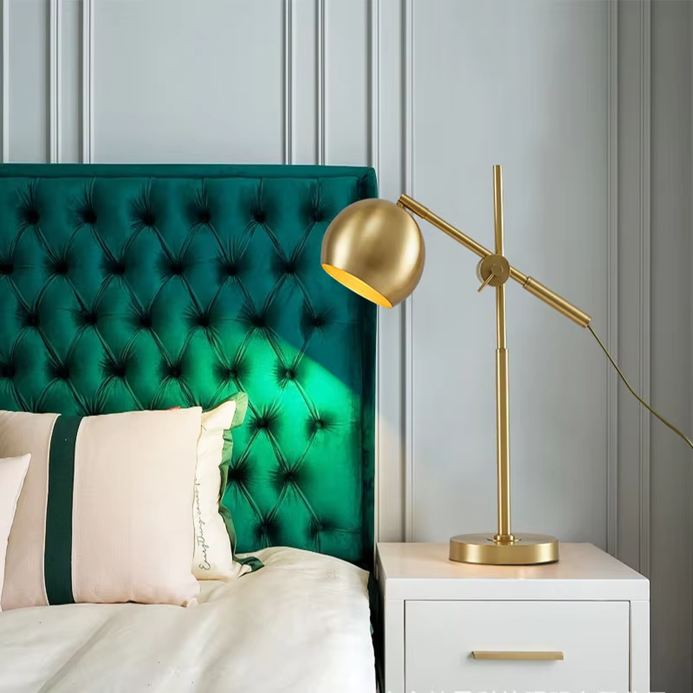 This is a modern light luxury style gold metal table lamp, featuring a spherical lampshade paired with an adjustable long arm and a stable base, which has both lighting and decorative functions, suitable for bedroom nightstands, study desks, hotel guest rooms and other spaces.
