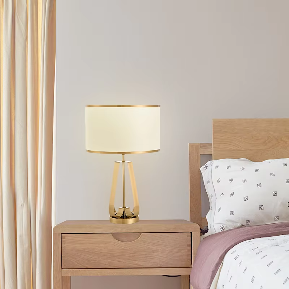 This is a light luxury geometric metal table lamp, featuring a gold polygonal hollow lamp base paired with an off-white fabric lampshade (with gold trim). It emits soft and warm light, serving both lighting and decorative purposes, suitable for bedroom nightstands, light luxury living room side tables, hotel guest rooms, showrooms and other scenarios.
