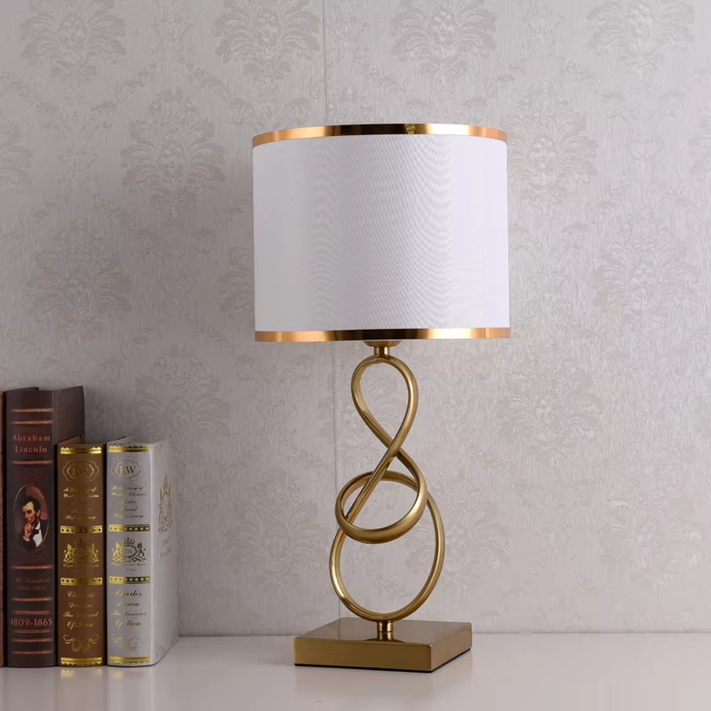 Modern light luxury twisted line metal table lamp, with a gold twisted line lamp pole paired with a beige fabric lampshade (with gold trim on the edge), a square gold base, emitting soft and warm light, combining decorativeness and practicality, suitable for lighting and decoration in spaces such as bedroom nightstands, living room side tables, and studies.