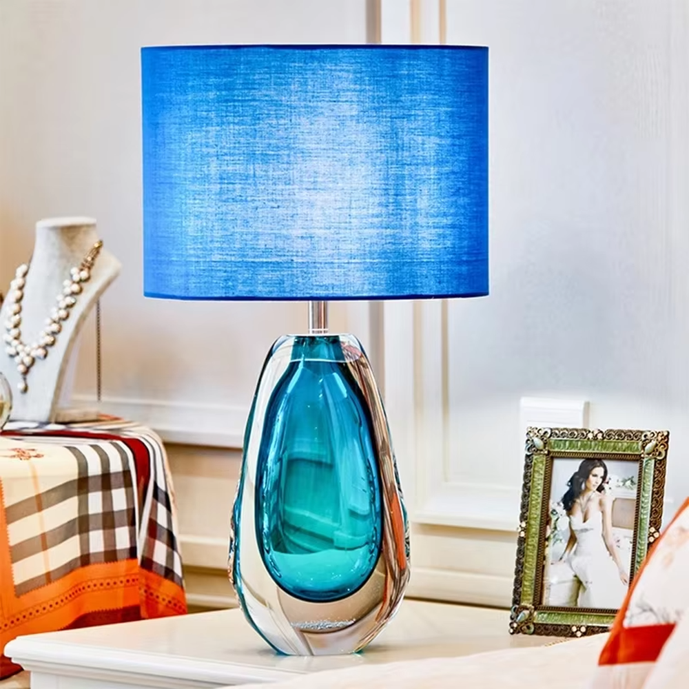 This is a fresh light luxury glass table lamp, with a royal blue fabric lampshade paired with a blue-green gradient hand-blown glass base, featuring both decorative and lighting functions, ideal for warm indoor scenarios such as bedroom nightstands and living room side tables.