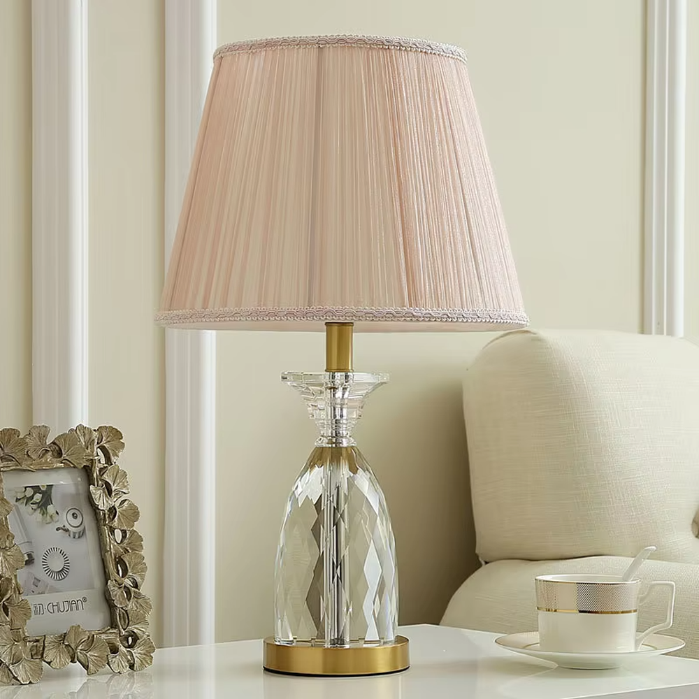 Light luxury crystal table lamp, with a diamond-cut crystal base, pink pleated fabric lampshade and gold metal details, providing soft and warm light, designed to enhance the elegant atmosphere of spaces, suitable for bedroom nightstands, living room side tables, princess rooms, etc.