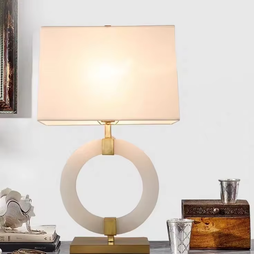 Light luxury white jade ring base table lamp, white jade-textured ring + golden metal decorations + white fabric lampshade, soft warm light, creating a light luxury elegant home atmosphere.