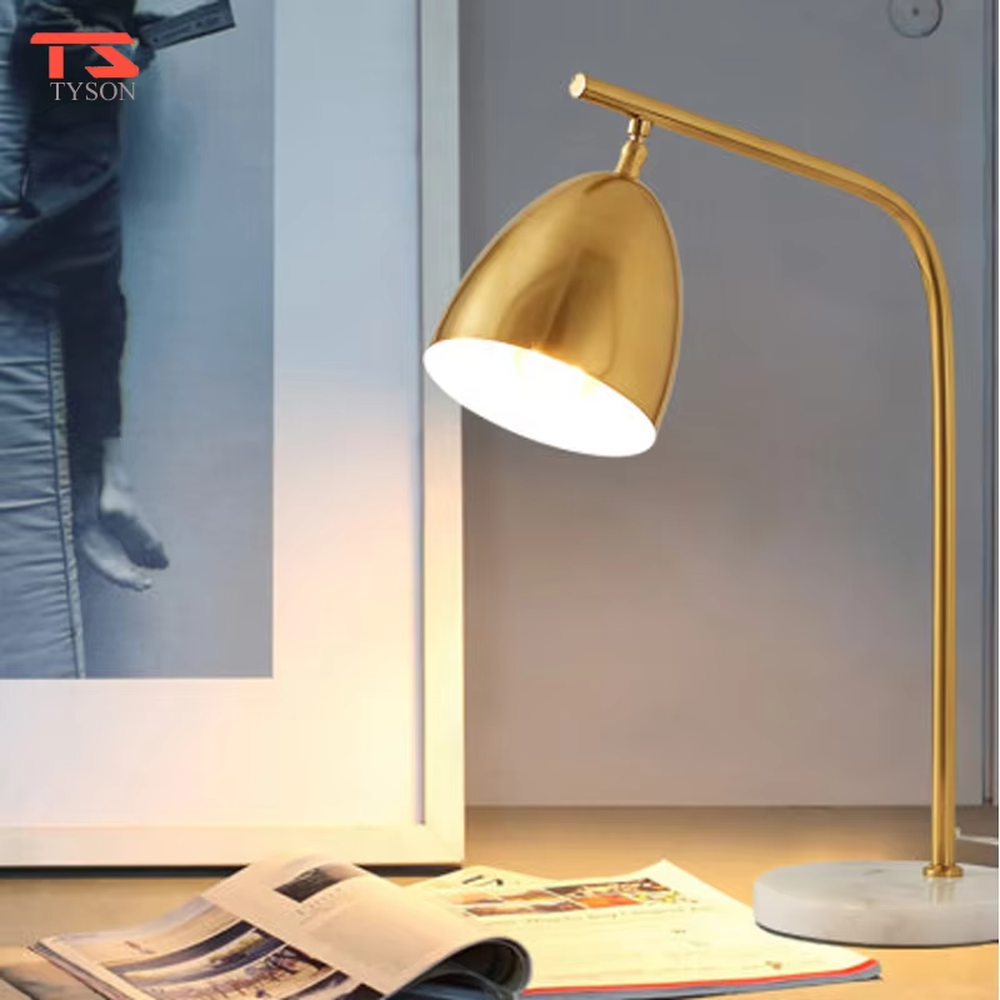 This is a modern light luxury style table lamp, with a gold metal curved arm paired with a dome-shaped lampshade, and a white marble base, which has both lighting and decorative functions, suitable for study desks, bedroom nightstands, office spaces, etc.
