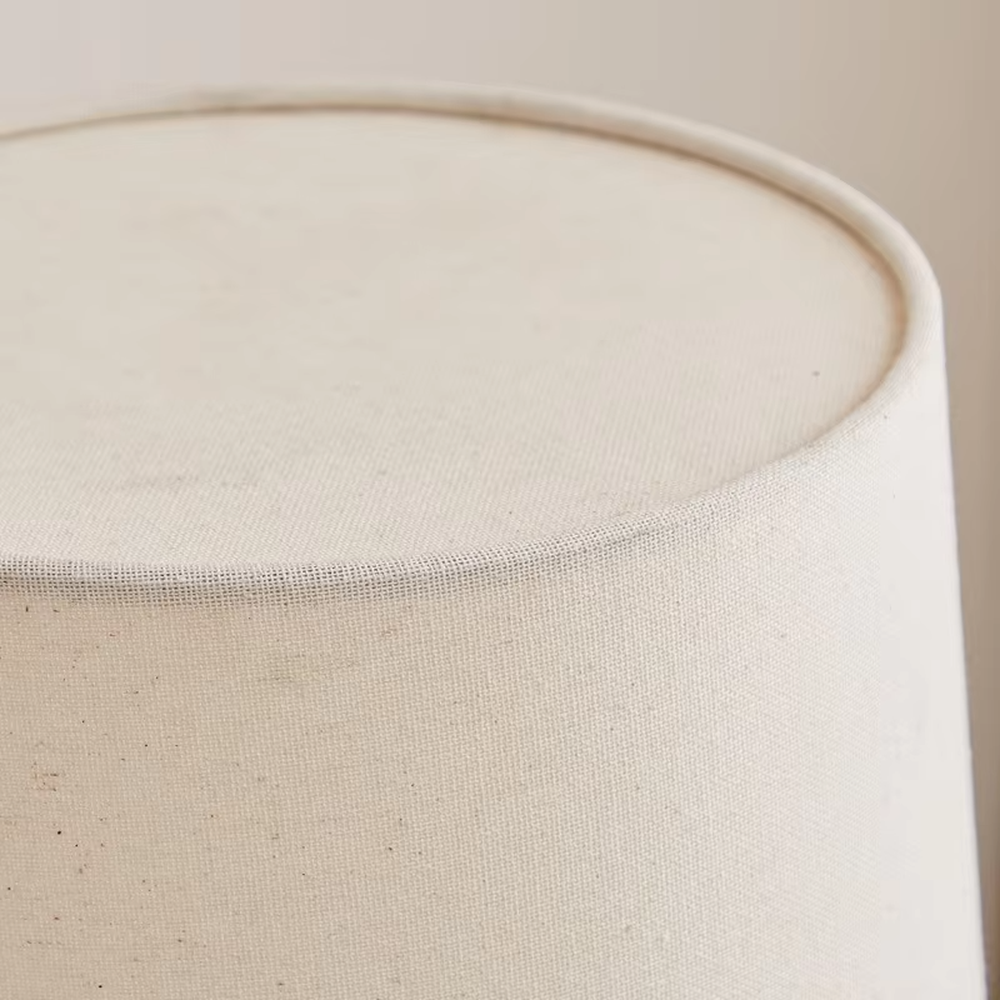 This is a minimalist light luxury table lamp, featuring an off-white linen fabric lampshade paired with a black and gold dual-color metal lamp pole, with a pull-chain switch. It emits soft and warm light, serving both lighting and decorative purposes, suitable for bedroom nightstands, living room side tables, studies, hotel guest rooms and other scenarios.