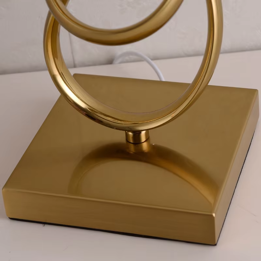 Modern light luxury twisted line metal table lamp, with a gold twisted line lamp pole paired with a beige fabric lampshade (with gold trim on the edge), a square gold base, emitting soft and warm light, combining decorativeness and practicality, suitable for lighting and decoration in spaces such as bedroom nightstands, living room side tables, and studies.