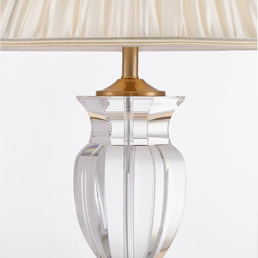 Light luxury crystal table lamp, with a transparent cut crystal column base, gold metal details and a beige pleated fabric lampshade for soft and eye-protective lighting, designed to enhance the elegant atmosphere of spaces, suitable for bedroom nightstands, living room side tables, hotel guest rooms, etc.