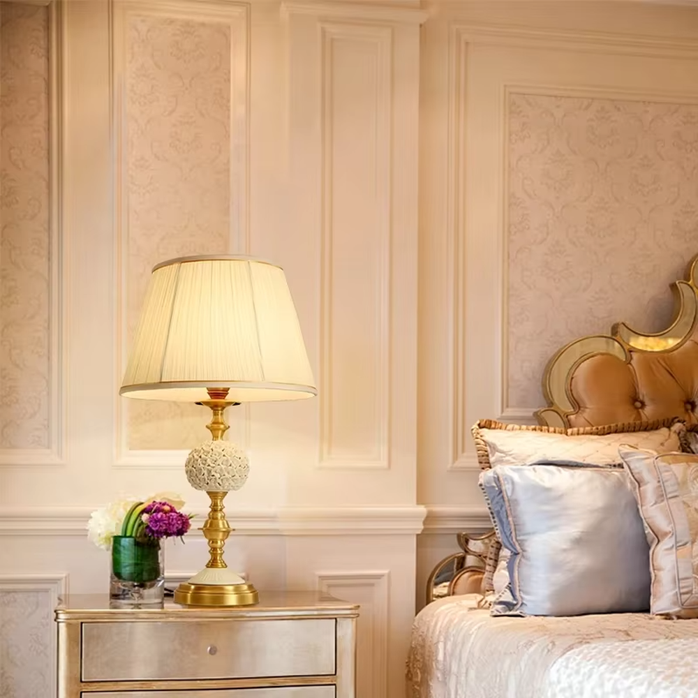 Vintage carved glass table lamp (brass stand + pleated fabric shade), warm light effect, creating an elegant vintage light luxury home atmosphere.