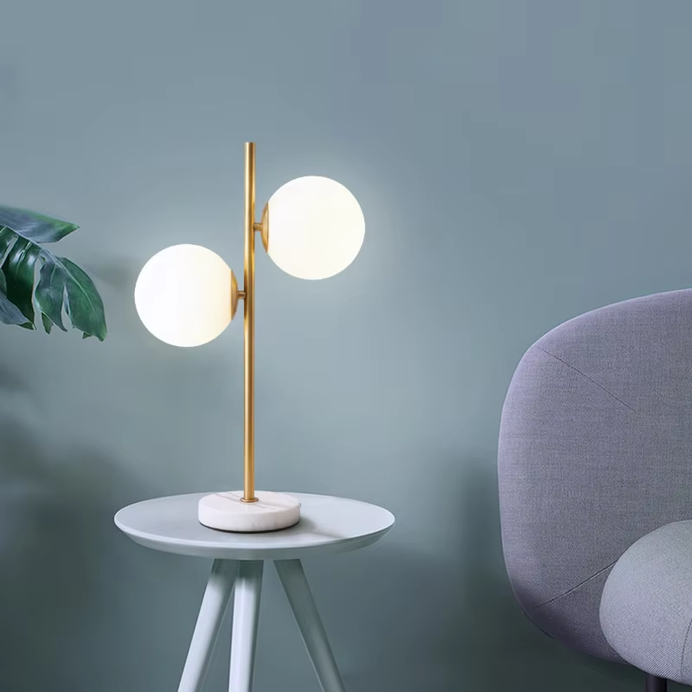 This modern light luxury double-ball table lamp features a gold metal stand, paired with milky white glass ball lampshades and a white marble base, with a simple and elegant staggered double-ball layout, serving both lighting and decorative purposes, ideal for living room side tables, bedroom bedside tables, light luxury homestays and other spaces.