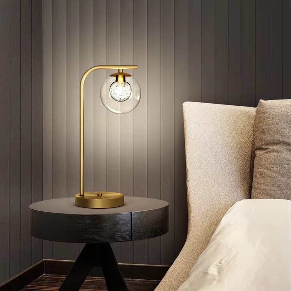 Modern light luxury golden curved pole transparent glass ball shade glitter bulb table lamp, warm light effect, creating a minimalist exquisite atmosphere.