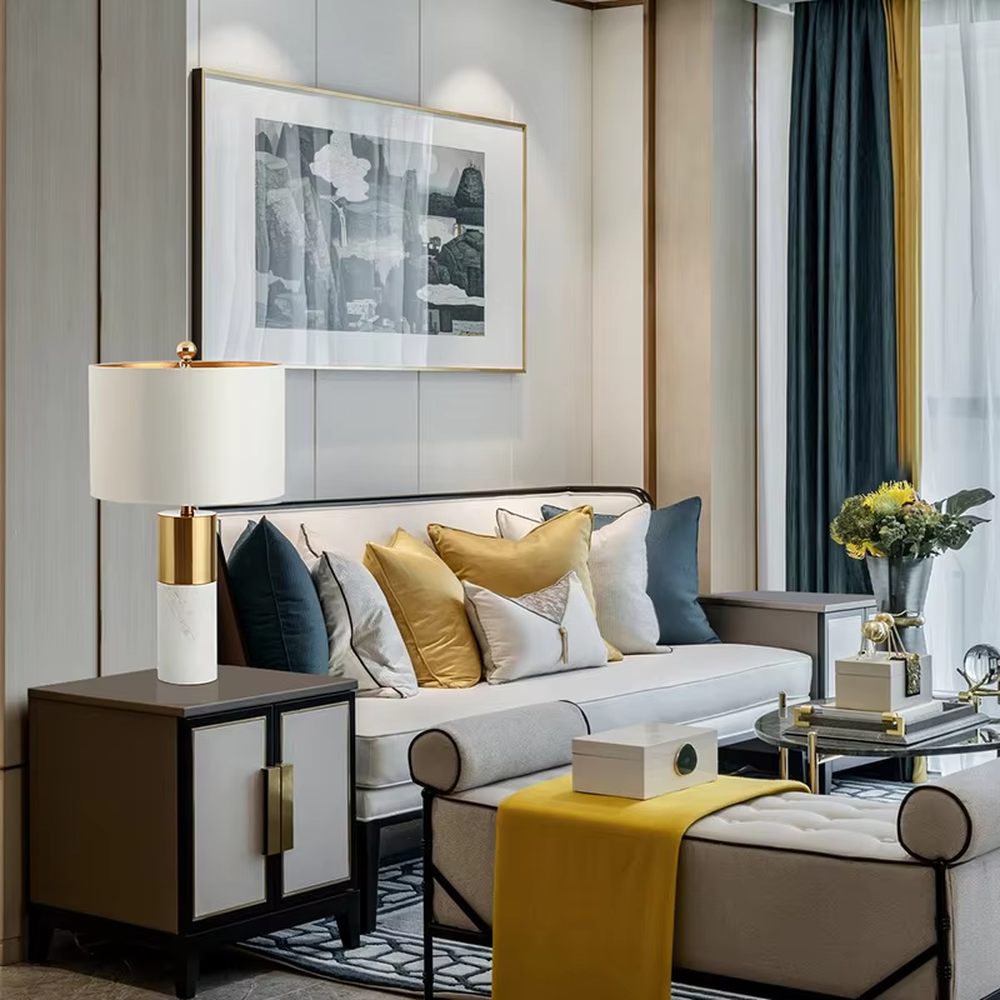 This light luxury table lamp features a black marble (with white veins) base, paired with a gold metal cylindrical lamp body and an off-white fabric cylindrical lampshade, with a gold spherical decoration on top. It serves both lighting and decorative purposes, ideal for light luxury spaces such as bedroom bedside tables, living room side tables, and hotel guest rooms.