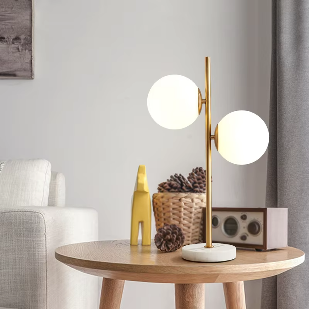 This modern light luxury double-ball table lamp features a gold metal stand, paired with milky white glass ball lampshades and a white marble base, with a simple and elegant staggered double-ball layout, serving both lighting and decorative purposes, ideal for living room side tables, bedroom bedside tables, light luxury homestays and other spaces.