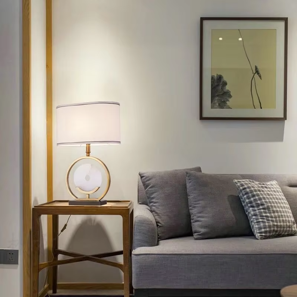 Modern light luxury gold ring white spherical base beige trimmed fabric shade table lamp, warm light effect, creating an elegant home atmosphere.