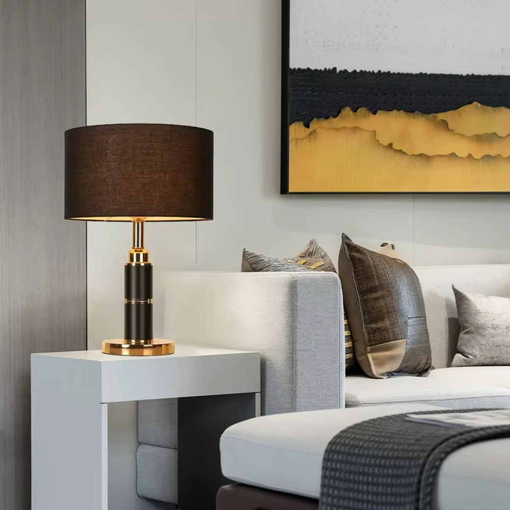Light luxury brown fabric shade black-gold cylindrical base table lamp, warm light effect, creating a calm and high-end space atmosphere.